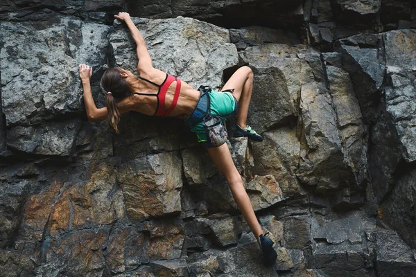 Joven delgado muscular mujer escalador escalada en la ruta deportiva difícil, escalador hace un movimiento duro . —  Fotos de Stock
