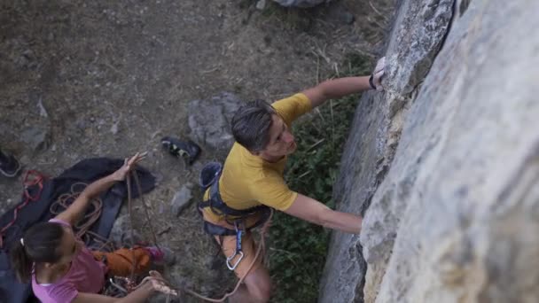 Joven escalador empezando a subir a un acantilado, buscando, alcanzando y agarrando asimiento . — Vídeo de stock