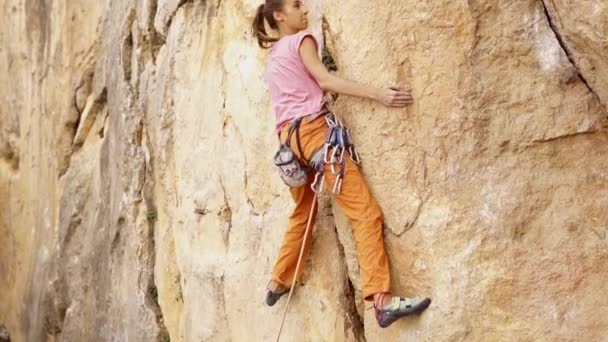 Joven escaladora tratando de escalar un acantilado, buscando, alcanzando y agarrando asimiento . — Vídeos de Stock