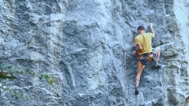 Kaya tırmanışçısı bir uçuruma tırmanmaya başlıyor. Arıyor, uzanıyor ve sıkıca tutuyor.. — Stok video