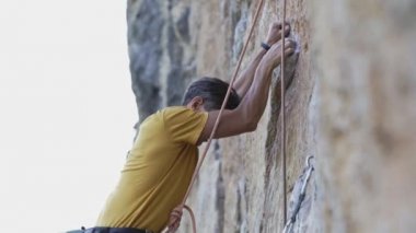 Genç kaya tırmanışçısı bir uçuruma tırmanmaya başlıyor. Arıyor, uzanıyor ve tutunuyor..