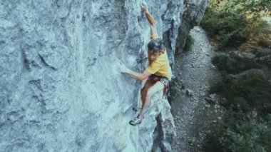 Kaya tırmanışçısı bir uçuruma tırmanmaya başlıyor. Arıyor, uzanıyor ve sıkıca tutuyor..