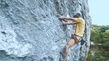 Kaya tırmanışçısı bir uçuruma tırmanmaya başlıyor. Arıyor, uzanıyor ve sıkıca tutuyor..