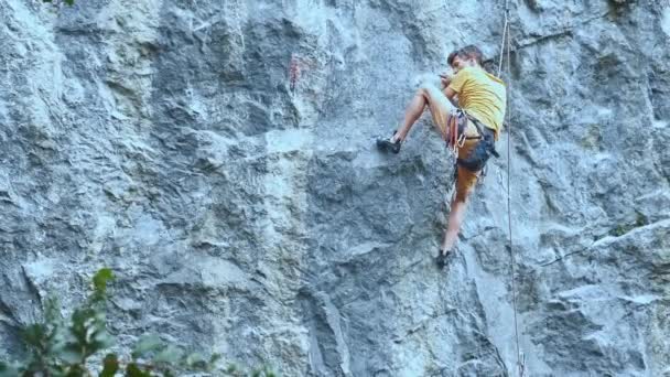 Hombre escalador de roca empezando a subir a un acantilado, la búsqueda, el alcance y agarre de retención . — Vídeo de stock
