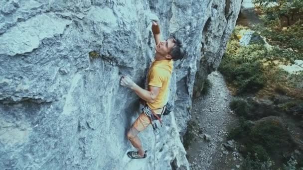 Hombre escalador de roca empezando a subir a un acantilado, la búsqueda, el alcance y agarre de retención . — Vídeo de stock