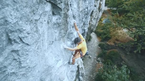 Homme alpiniste commence à grimper sur une falaise, la recherche, atteindre et saisir . — Video