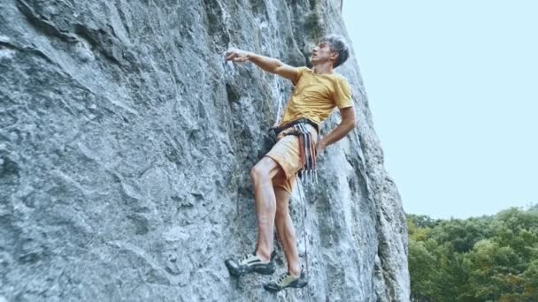 Człowiek alpinista wiszący na linie na trudnej trasie sportowej, odpoczynku i kredy ręce. — Wideo stockowe