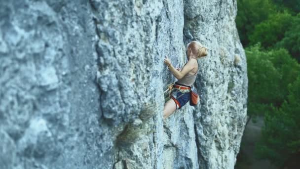 Sportlerin mit farbigen Haaren klettert den Felsen hinauf und trainiert in den Bergen. — Stockvideo