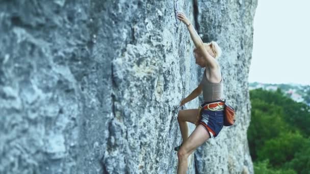 山の中でワークアウトを持っている岩を登る色の髪を持つスポーツ女性. — ストック動画