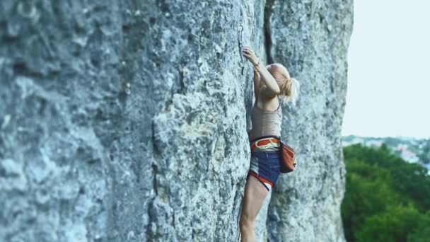 Sportlerin mit farbigen Haaren klettert den Felsen hinauf und trainiert in den Bergen. — Stockvideo