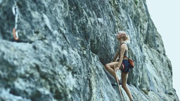 Deportiva mujer con el pelo de color escalada la roca teniendo entrenamiento en las montañas . — Vídeo de stock