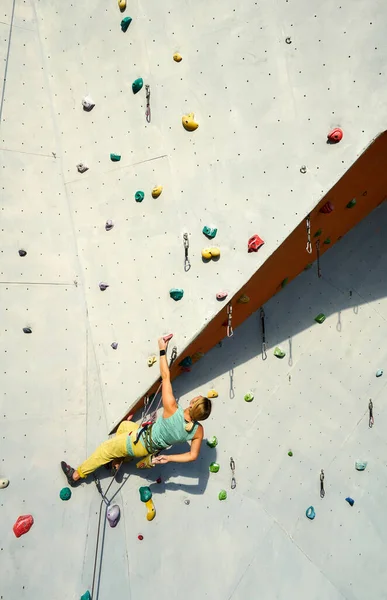 운동 여자등 산가가 운동을 하고, 운동을 하고, 쉬고, 손을 칠 때 인공 바위 벽에 바위를 타고 오르는 연습을 하고 있다. — 스톡 사진