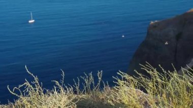 Mavi denizin üzerinde yüksek kireçtaşı uçurumları ve berrak mavi gökyüzü olan deniz manzarası.