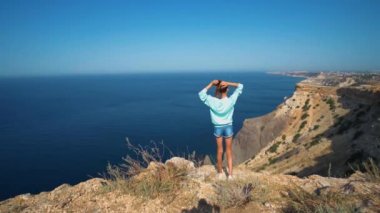Dağın tepesinde kolları havada bir kadın gezgin.