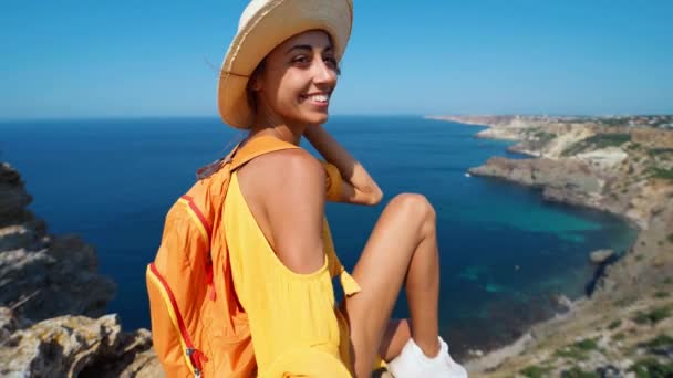 Felice donna abbronzata atractive posa con mano allungando sul bordo della scogliera con bella vista sul mare . — Video Stock