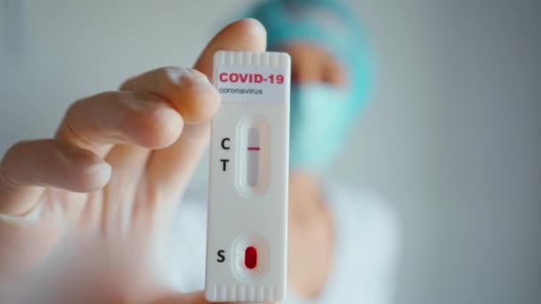 Médico ou enfermeiro em máscara protetora e luvas segurando teste kit de cartão de laboratório para doença viral COVID-19 — Vídeo de Stock