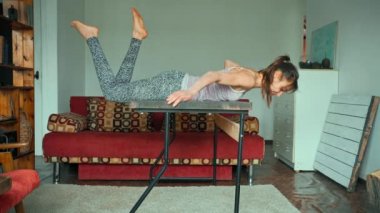 Güçlü ve çevik sporcu kadın tahta masanın etrafına tırmanıyor.