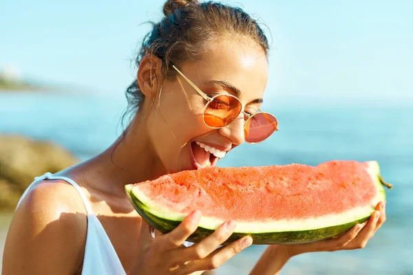 Summer muotokuva hauska tyttö punaisissa laseissa tilalla valtava siivu vesimelonia ja puree häntä ilo. — kuvapankkivalokuva