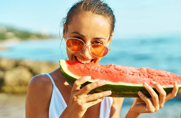 Lähikuva muotokuva kesän nainen punaisissa laseissa hauska syöminen vesimeloni, puree häntä ilo — kuvapankkivalokuva