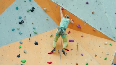 güçlü kadın kaya tırmanışçısı dikey yapay kaya duvarına tırmanıyor.