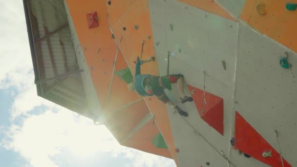 Escalador escalada en la pared de roca sobresaliente en el centro de escalada al aire libre — Vídeos de Stock