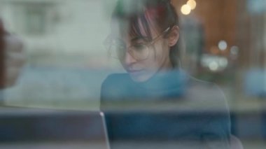 Ofiste dizüstü bilgisayarda yazan gri bir kazak giyen genç bir kadın.