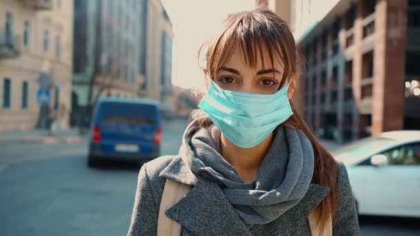 Primo piano e zoom fuori attraente giovane donna caucasica in maschera medica protettiva guardando dritto — Video Stock