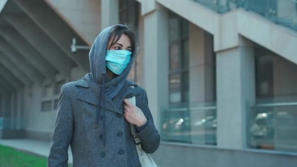 Mujer en la máscara facial para la protección coronavirus caminando en la calle de la ciudad — Vídeo de stock