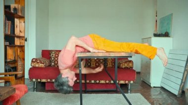 Güçlü ve çevik sporcu adam tahta masanın etrafına tırmanıyor.