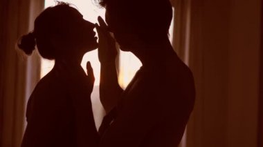 Siluet çift aşıkları birbirine dokunuyor ve pencereye nazikçe sarılıyorlar.