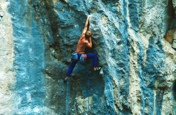 Sportmann Bergsteiger mit muskulösem Rücken und kräftigem Körper klettert auf die leuchtend bunte Felswand — Stockfoto