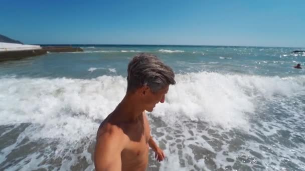 Lachender, braun gebrannter, fröhlicher Mann, der beim Strandspaziergang ein Video-Selfie macht — Stockvideo