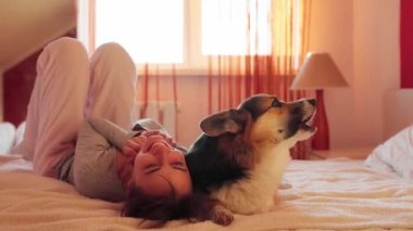 Sevdiği köpeği Galli Corgi ile yatakta yatan mutlu kadının yakın plan portresi..