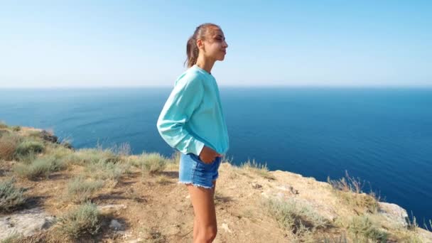 Movimento da câmera em torno de uma jovem mulher de pé no fundo da costa incrível — Vídeo de Stock