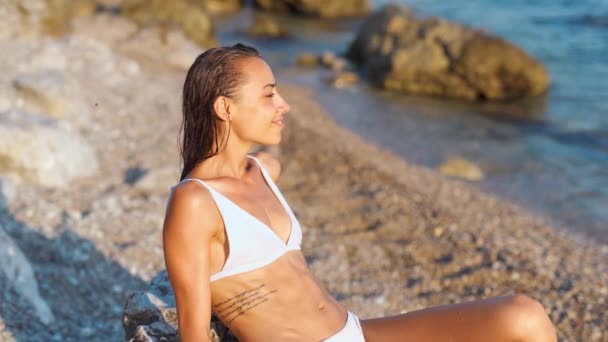 Σέξι γυναίκα με τέλειο σώμα σε λευκό μπικίνι χαλαρώνοντας στην παραλία την ηλιόλουστη μέρα — Αρχείο Βίντεο
