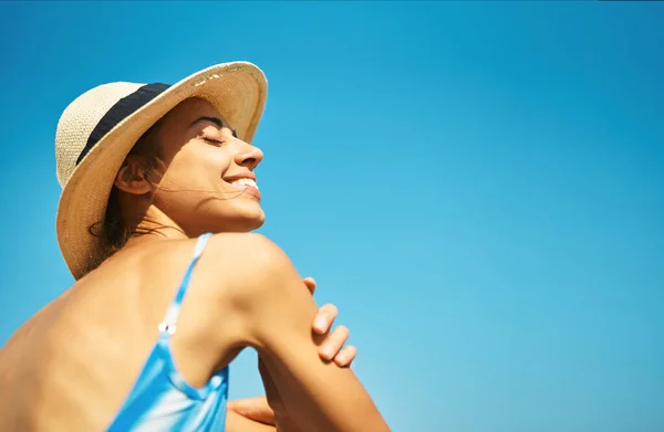 Avslappet kvinne med hatt som nyter sommerferie på stranden. – stockfoto