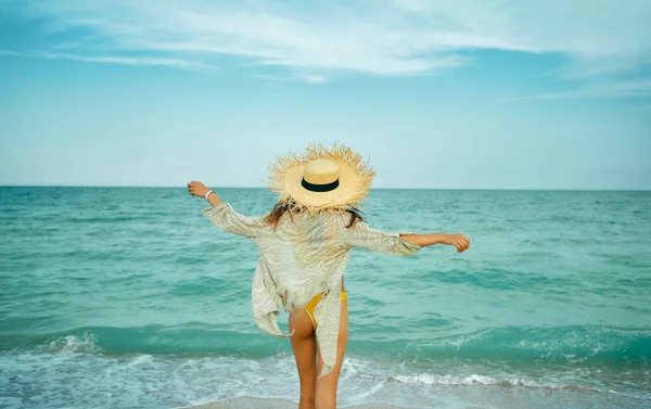 Strandsommer stilvolles Mädchen in glücklichem Freiheitskonzept, das mit offenen Armen am blauen Meer mit Wellen steht. — Stockfoto