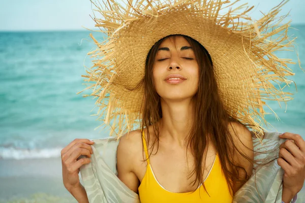 Nærbilde utendørs moteportrett ung kvinne iført stor stråhatt på havet på tropisk strand – stockfoto