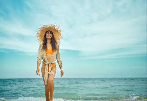 Mujer latina sonriente en bikini naranja brillante y sombrero de paja sobre fondo de mar — Foto de Stock