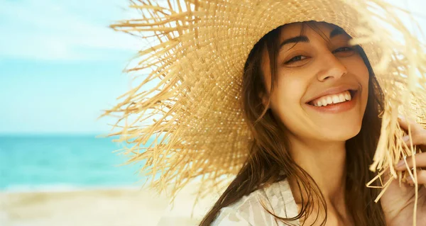 Lähikuva kasvot hymyilevä nainen yllään olkihattu rannalla auringonpaisteessa auringonnousu meren rannalla. — kuvapankkivalokuva