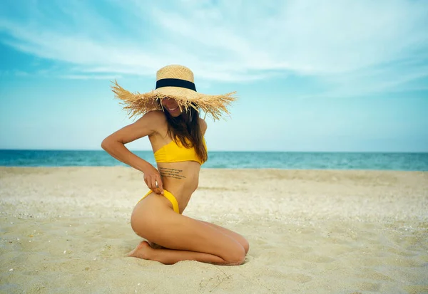 Side view gyönyörű barna lány homokos strandon visel szalma kalap. — Stock Fotó