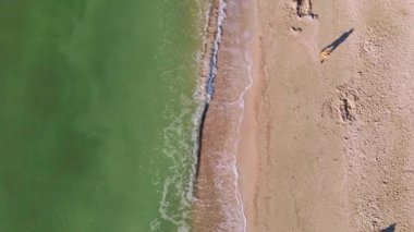 Güneşli bir yaz sabahı kumsalda okyanus kenarında koşan yalnız bir adam..