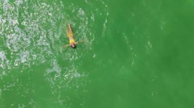 İnsansız hava aracı görünümlü kadın sakin denizde yüzüyor.