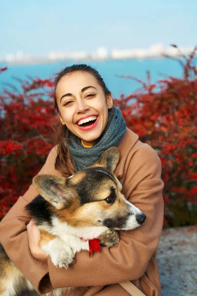 Portrait happy girl with her pet Welsh Corgi dog on autumn nature background with red fall leaves. — Stock Photo, Image