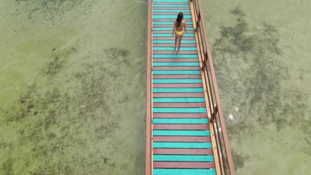 Sexy brunetka kobieta w żółty bikini spacery na drewniany most — Wideo stockowe