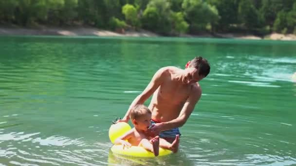 Atlético hombre feliz divirtiéndose con el niño en el lago de montaña — Vídeos de Stock