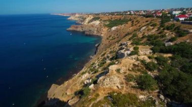 Mavi denizin üzerinde yüksek kireçtaşı kayalıkları olan deniz manzaralı bir yer.