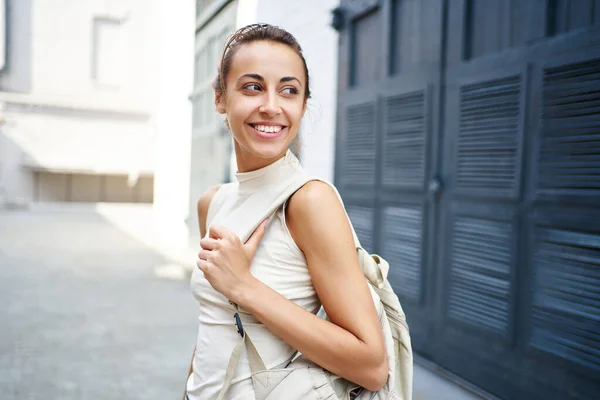 Retrato de cerca de una mujer alegre sonriendo y mirando hacia otro lado sobre el fondo urbano de la calle. — Foto de Stock