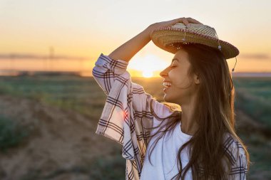 Günbatımında doğa manzaralı mutlu hipster kadın portresi. Hippi Treveler kız şapka takıyor.