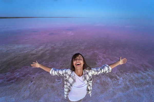 Feliz mujer gozosa disfrutando del paisaje natural en el lago de sal rosa por la noche — Foto de Stock